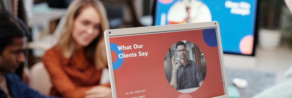 A team reviewing client feedback on a laptop screen, with a presentation titled "What Our Clients Say" showing a satisfied customer.