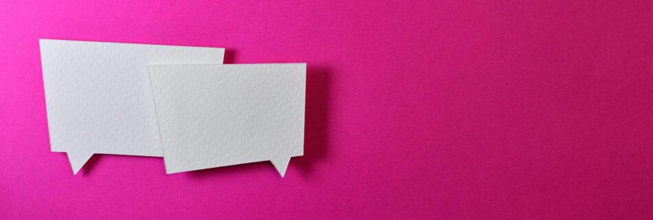 Two white paper cutouts shaped like chat bubbles placed on a bright pink background, symbolizing communication or conversation.