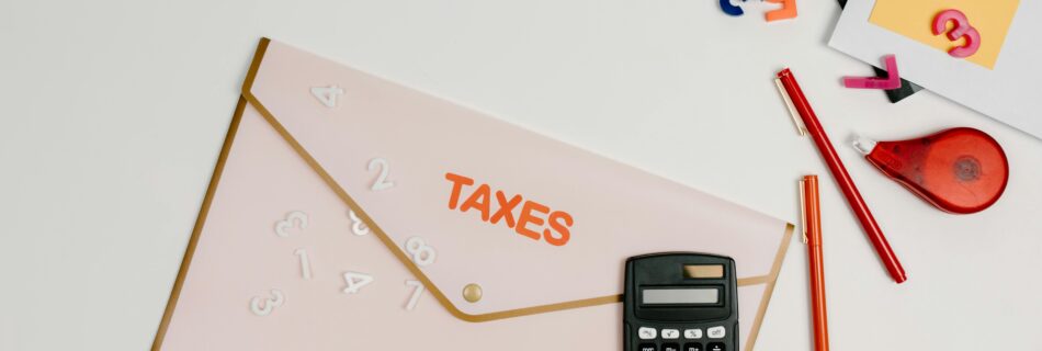 Tax folder with calculator and colorful office supplies on a desk.