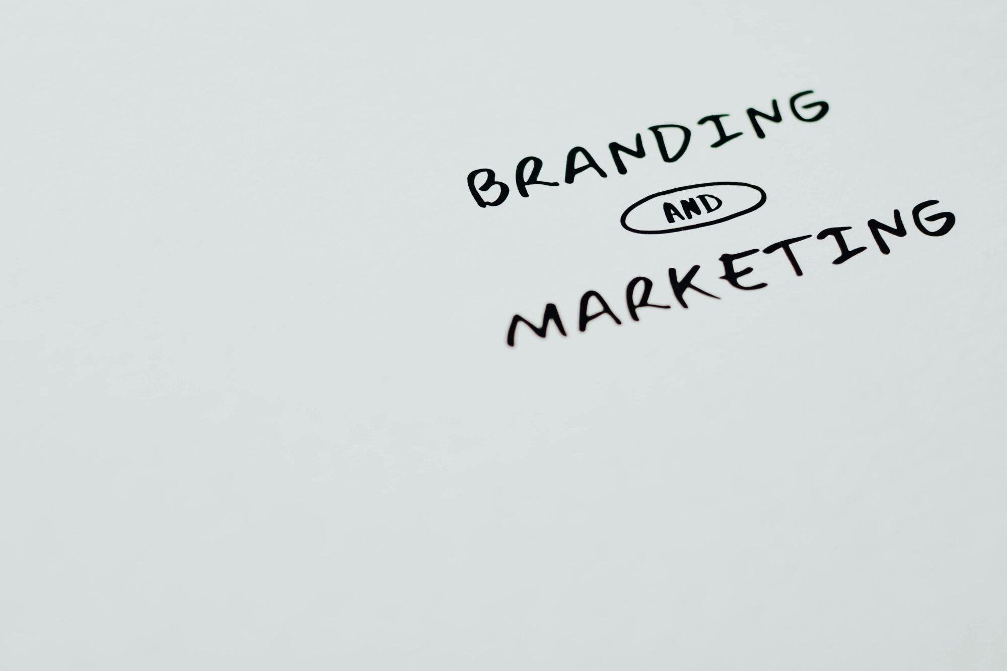 Handwritten text displaying "Branding and Marketing" on a white surface, emphasizing the importance of these concepts in business growth.