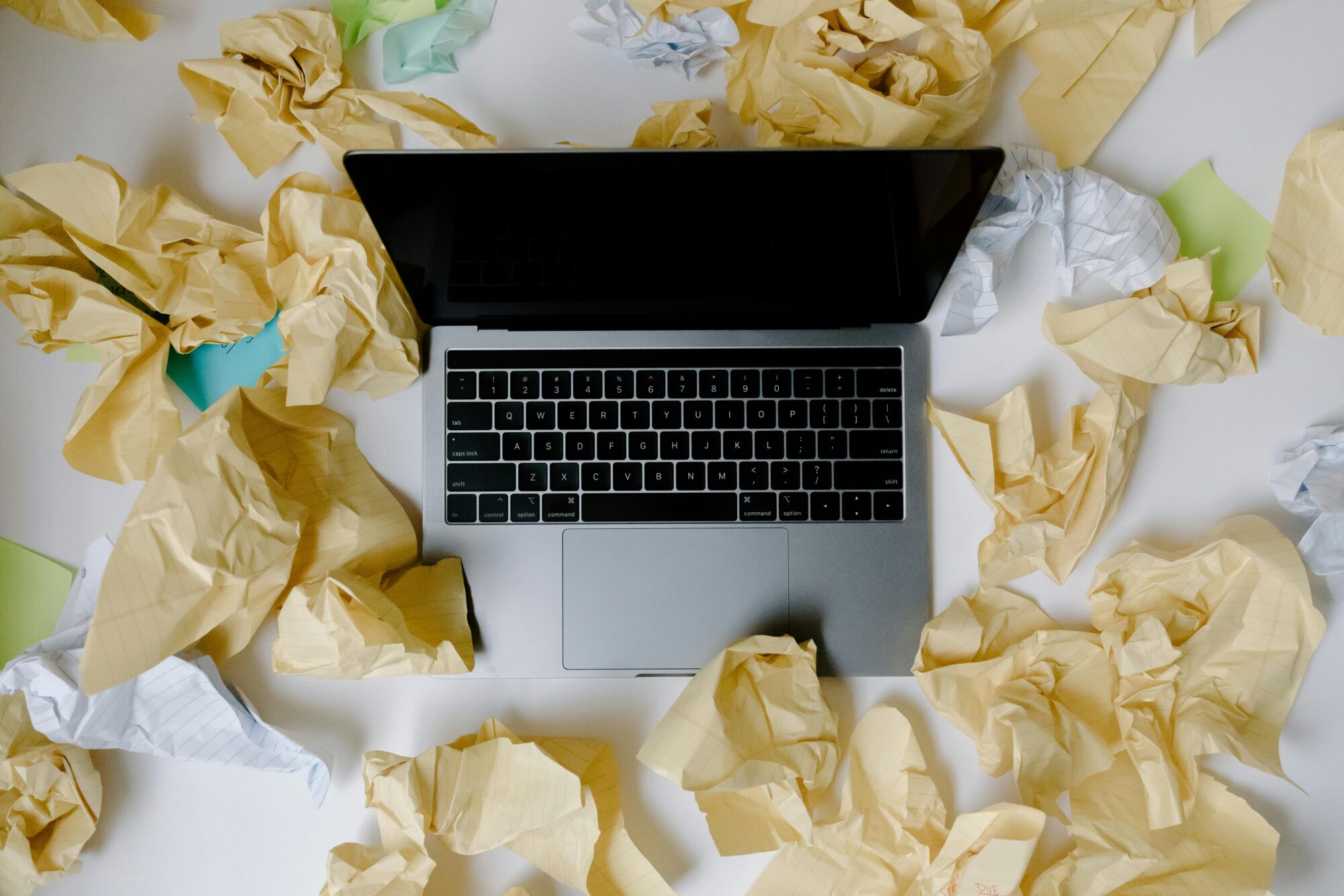 A laptop surrounded by crumpled papers, symbolizing business chaos and disorganization.