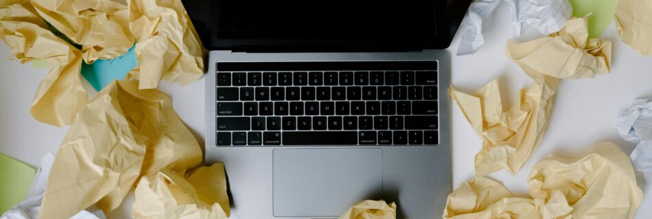 A laptop surrounded by crumpled papers, symbolizing business chaos and disorganization.