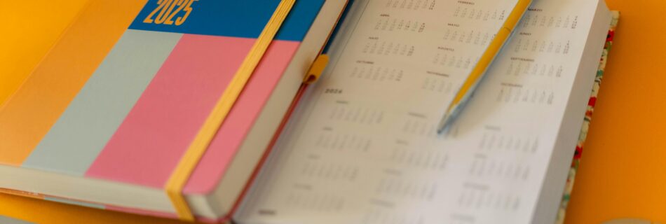 Colorful 2025 planner with a pen and keyboard on a yellow background