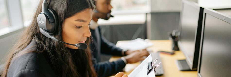 Virtual assistants wearing headsets, working on computers and taking notes in a modern office.